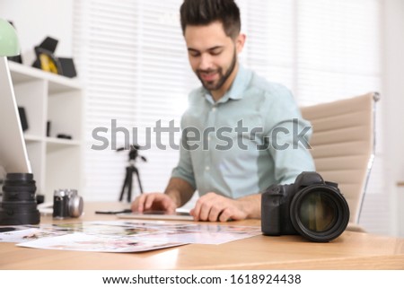 Professional photographer working at table in office, focus on camera