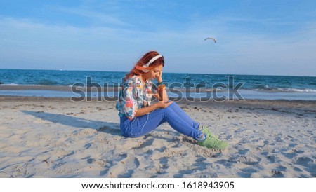 Young woman with colorful hair walk on the summer beach and listen music with headphones	