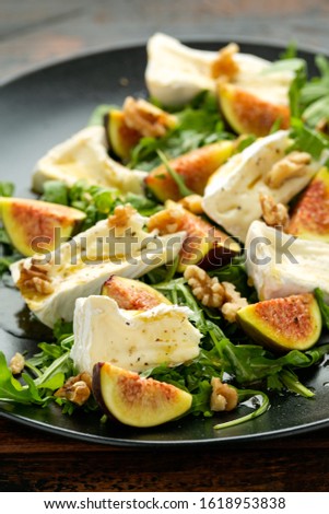 Vegetarian camembert cheese, fig and Arugula, hot rocket salad served on black plate