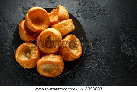 Traditional English Yorkshire pudding side dish on black plate and background Royalty-Free Stock Photo #1618953883
