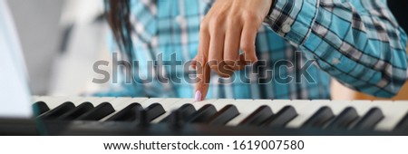 Focus on female hand playing synthesizer in music studio. Professional cute pianist learning new musical composition. Art and music concept. Blurred background