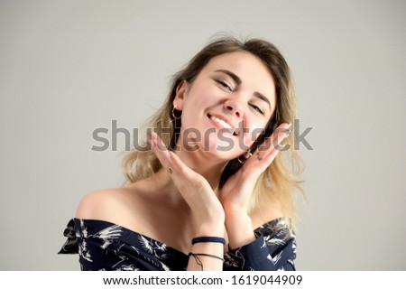 Close-up photo Portrait of a girl model with excellent makeup with good teeth in the studio on a white background. Concept woman in a dark shirt smiles and talks.