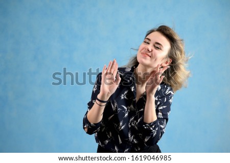 Concept woman in a dark blouse smiling talking. Portrait of a model girl with excellent makeup with curly hair and good teeth in the studio on a blue background.