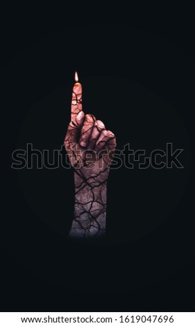 Demonic hand lighting the dark with his index finger. Eroded arm with a texture of cracks.