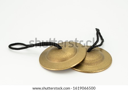 Closeup of a pair of finger cymbals lying on a white underground Royalty-Free Stock Photo #1619066500