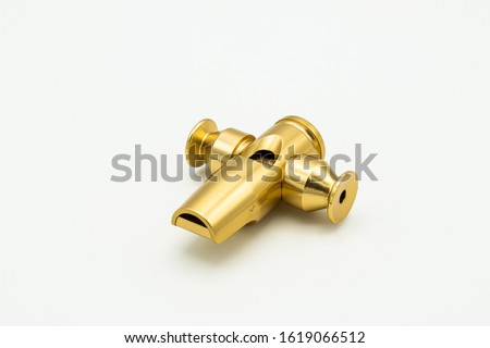 Closeup of a golden samba whistle lying on a white underground