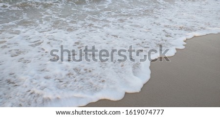 photo of the beach that show white foam waves and brown color sand