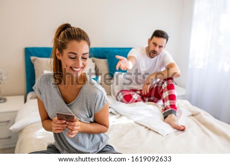 Jealous man looking in girlfriend phone while she texting a message, relationship problem. Husband is frustrated, upset while his internet addict wife is using mobile phone in social network