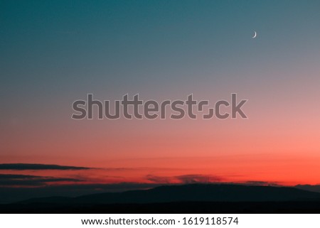 A minimalist view from the colorful sunset. Different shades of pink and blue with the small moon high in the sky.