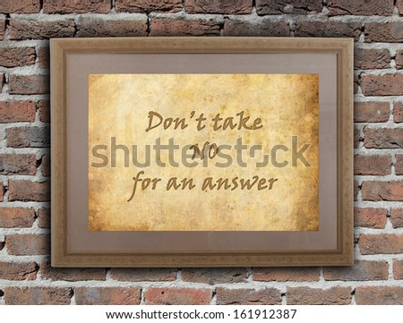 Old wooden frame with written text on an old wall - Don't take no for an answer
