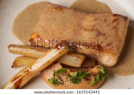 Baked Sturgeon fillet with spinach on a white plate on gray table background with copy space, close-up