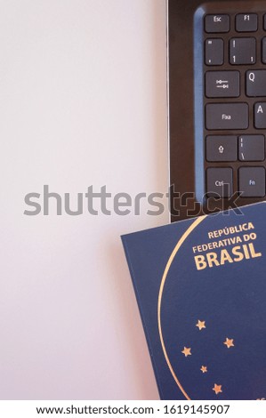 Vertical photo of laptop with Brazilian passport. Travel and business concept.