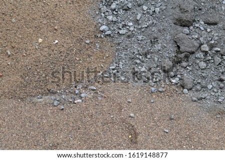 Construction materials in a construction site. In this photo you can see brown sand and grey crushed grey stone material. Closeup color image with beautiful textures.