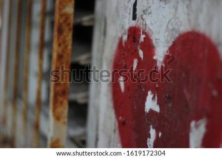 Red color heart graffiti on a brick wall background. Urban red heart graffiti. A symbol of a paint graffiti love Emotionm Valentine Day. Red heart graffiti painted on a street wall. Close up red heart