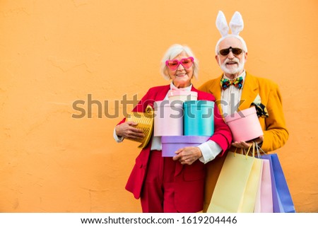 Waist up of happy senior couple in funny clothes with presents stock photo