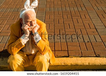 Distressed old male in in bunny hairband outdoors stock photo