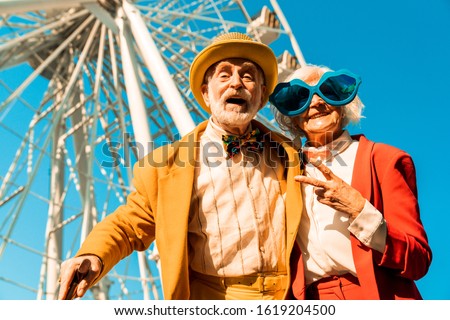 Happy joyful old couple in funny accessories near attraction stock photo
