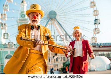 Happy adult man and woman wearing funny accessories near attraction in the city stock photo