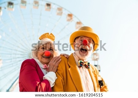 Waist up of happy funny elderly husband and wife wearing clown noses stock photo