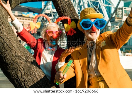 Smiling senior couple in funny clothes having great time in city stock photo