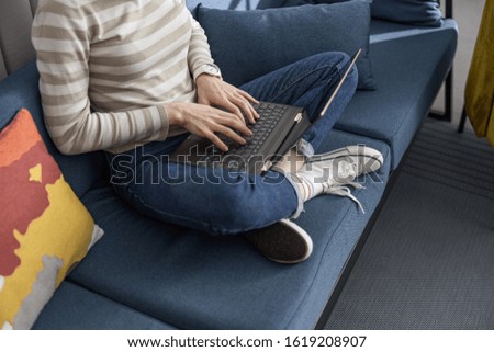 Cropped photo of female hands typing on gadget while sitting on sofa stock photo