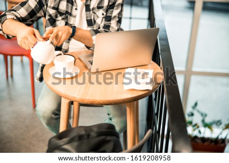 Cropped photo of male enjoying tea while working in coffee house stock photo