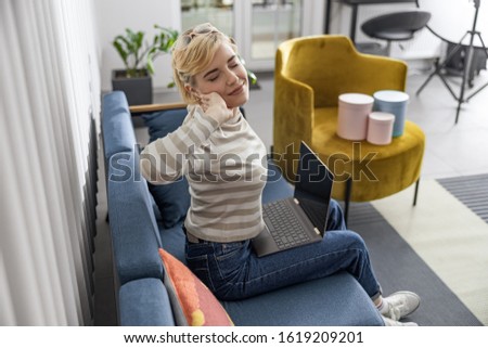 Smiling lady tired of work and stretching while staying at home stock photo