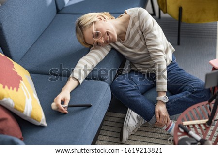 Happy pretty woman leaning on a sofa while holding a makeup brush stock photo