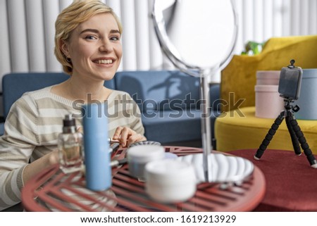 Waist up of smiling female blogger using smartphone while making video stock photo