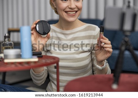 Cropped happy pretty lady holding cosmetics while making vlog stock photo