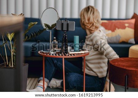 Back view of lady using smartphone for her vlog at home stock photo