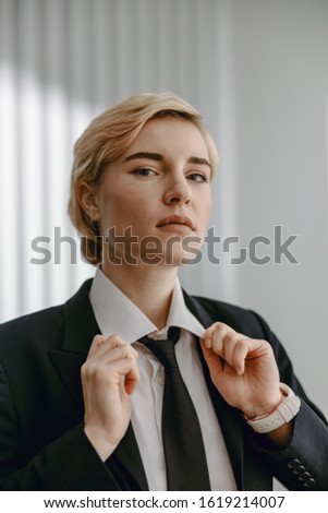 Waist up of stylish businesswoman holding shirt collar by hands stock photo