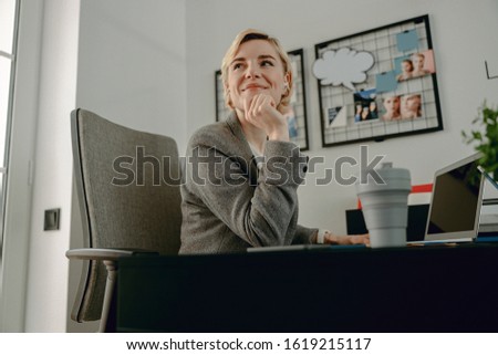 Waist up of happy pretty woman working with laptop at workplace stock photo