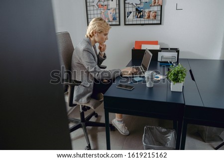Side view of pretty lady typing on laptop at workplace stock photo