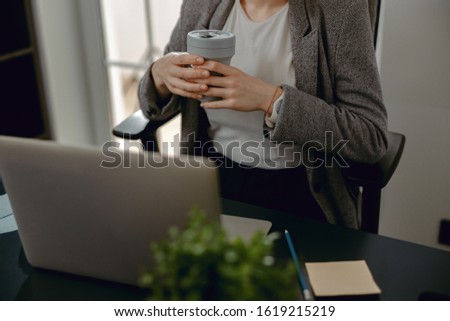 Cropped photo of young woman sitting at deskop while enjoying coffee stock photo