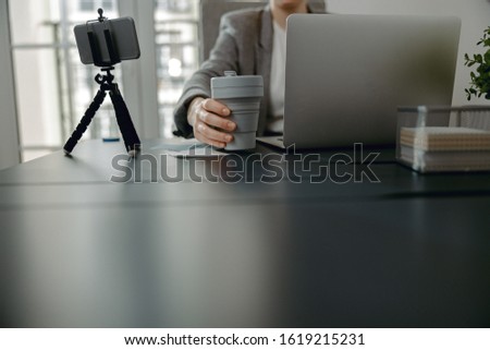 Cropped photo of female hand holding coffee while working with laptop stock photo