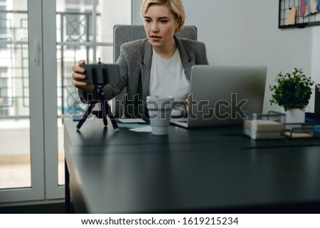 Waist up of pretty lady sitting in the office while making video stock photo
