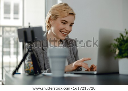 Waist up of happy lady typing on computer while sitting in her office stock photo