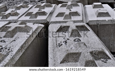 Large concrete blocks with crosses, covered in snow.  Used for retaining walls.  Interesting gothic cross pattern.
