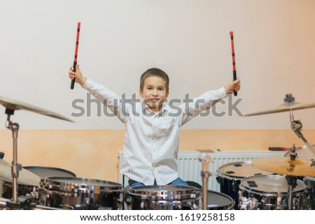 Boy drumming. boy in a white shirt plays the drums. A boy in a white shirt is drumming