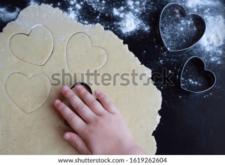 
A child makes cookies in the shape of a heart