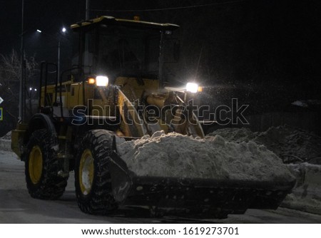 tractor removes snow at night