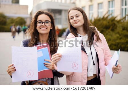 Grade / test results. Female students showing papers with perfect test result grade A, excellent mark for examination Royalty-Free Stock Photo #1619281489