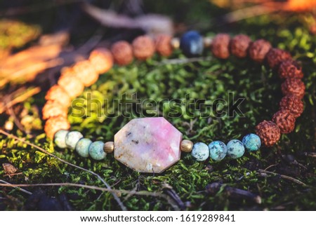 Beautiful female bracelet with fazeted opal stone and rudraksha seed on natural forest background