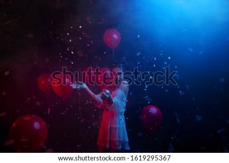 woman in clown costume laughs fun at party with neon red blue light, explodes spangles falling serpentine fall. happy joy Smile on pretty greasepaint face creative art make-up. Halloween animator 
