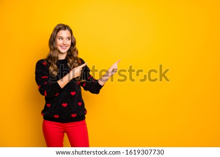 Photo of beautiful lady indicating hands fingers empty space advising low shopping season prices wear hearts pattern pullover red pants isolated yellow color background