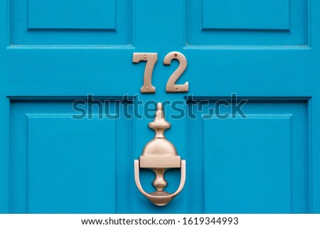 House number 72 on a beautiful blue wooden front door with door knocker