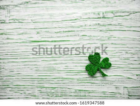 St. Patrick's day. Shiny Shamrock, clover leaf on a light wooden background.