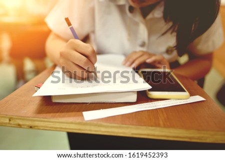 Student working on studying subject assignment, selective focused picture of college learner doing a class work, girl writing on piece of papers on the topic related to her course, education concept