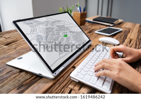 Close-up Of A Businessperson Analyzing Cadastre Map On Computer In The Office
